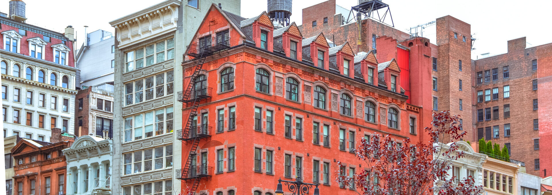 Colorful Brick Buildings, With Windows And Fire Stairs. Water Deposits On Rooftops. Nyc, Usa