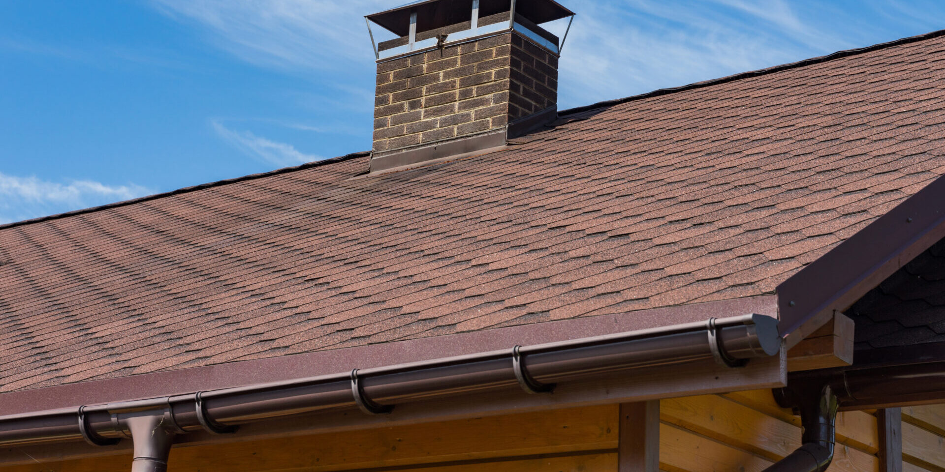 Bitumen Asphalt Roofing Shingles And Brick Chimney Pipe On A Wooden House. Individual Heating System. Rain Gutter.